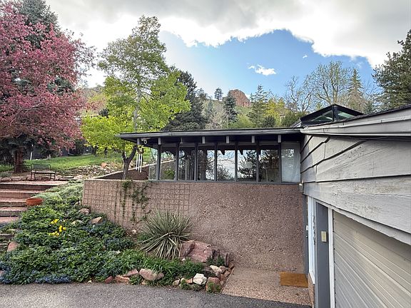 Exterior view of the home with Red Rocks hiking and climbing area in view above.