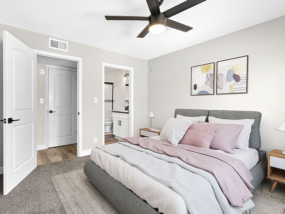 Carpeted bedroom with ceiling fan and private bathroom.
