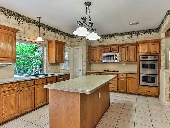 Island kitchen offers double oven, gas range, stainless steel appliances and breakfast bar with views of the backyard.