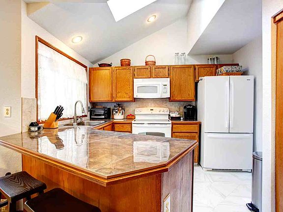 The updated kitchen has vaulted ceilings, a skylight, pantry, braekfast bar & white appliances. The beautiful counters are porcelain tile.