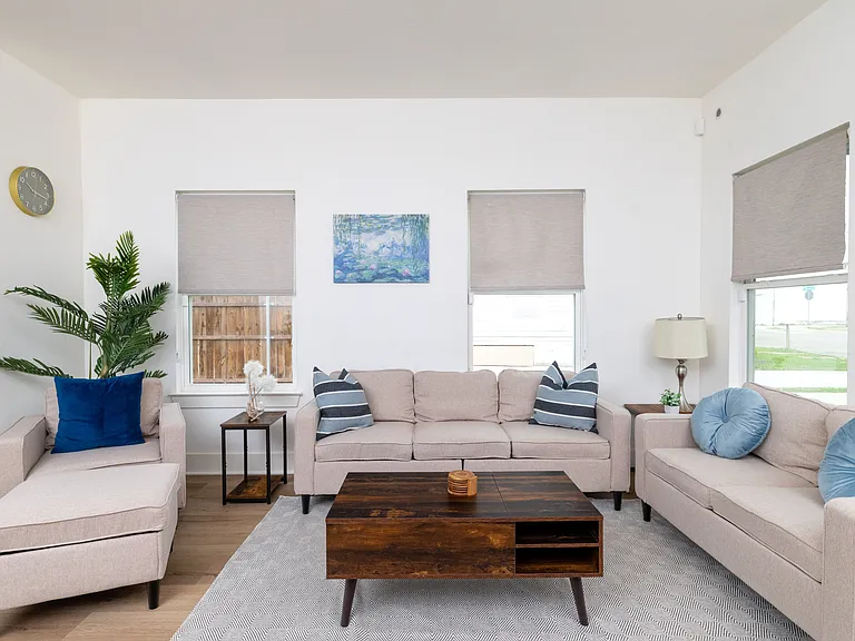 Relax in this bright, open-concept living room featuring a spacious L-shaped sectional ideal for group lounging or family movie nights.