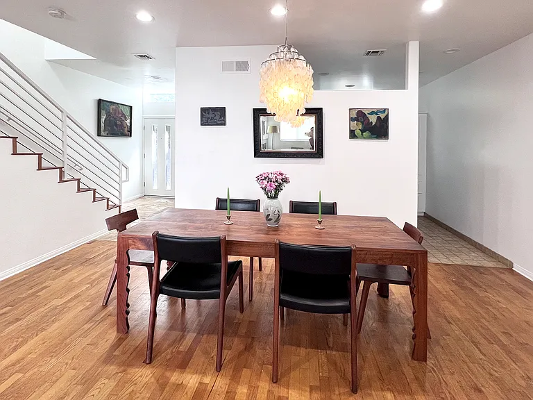 Bright open-concept living and dining space featuring real wood floors, accented by high ceilings with curated recessed lighting, artistic designer furniture, and chandelier.