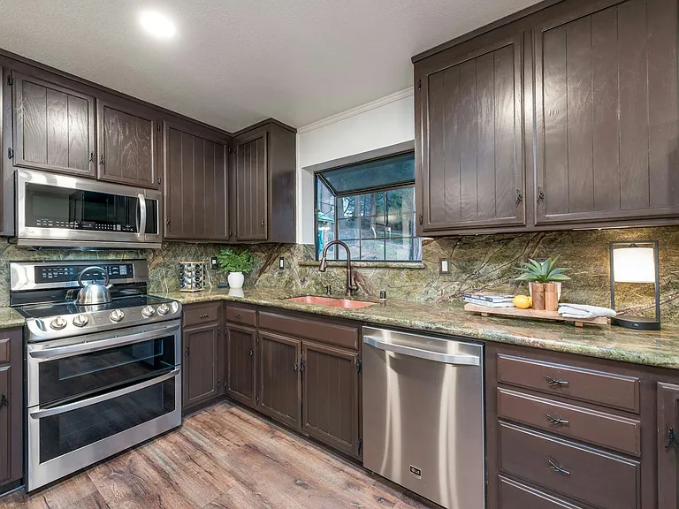 Kitchen with stainless steel dish washer, electric stove, oven and microwave.