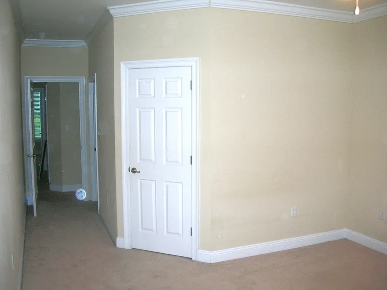 Master bedrrom showing door to walk in closet, door down hall on right to master bathroom.