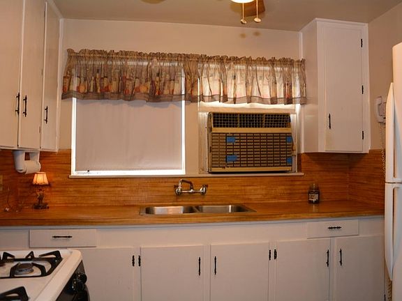 Pretty white cabinets with butcher block laminate counter tops.