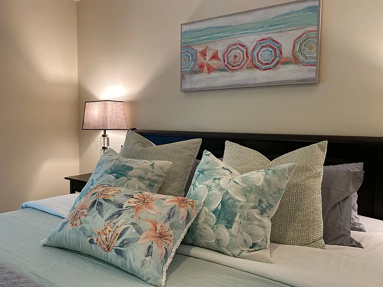 Inviting bedroom with a padded headboard, nightstand lighting, and tasteful wall art for a relaxing retreat.