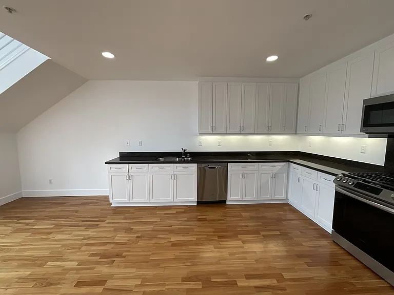 Newly painted cabinets with stainless steel appliances: dishwasher, gas range, microwave and refrigerator.