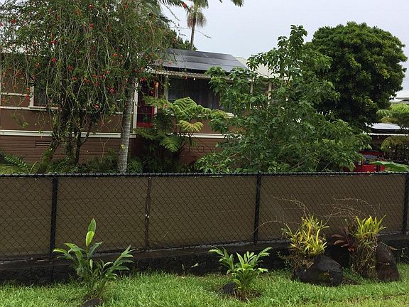 Fully fenced front yard with rock wall, chain link, privacy screen, and landscaping