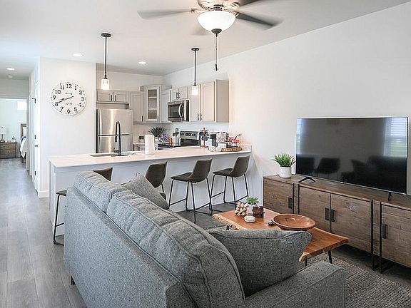 Modern open-concept living space with a stylish kitchen, cozy sofa, chic dining area, and elegant decor.