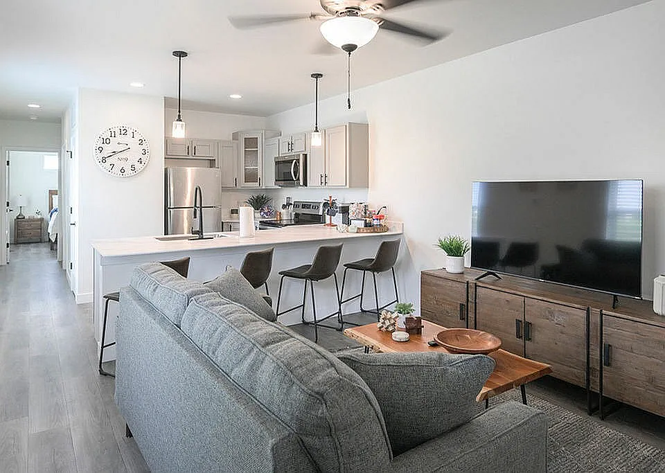 Modern open-concept living space with a stylish kitchen, cozy sofa, chic dining area, and elegant decor.