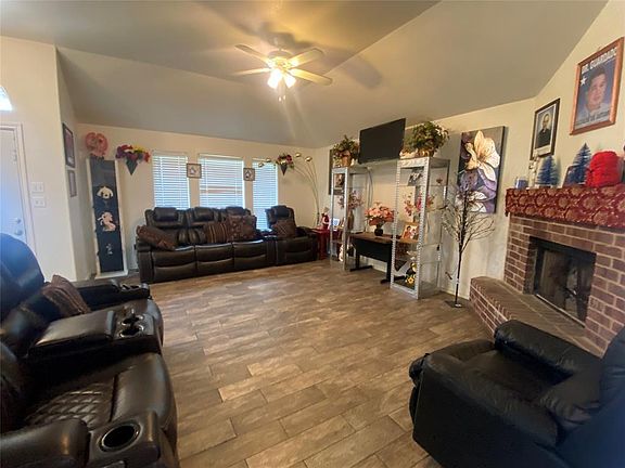 Living room featuring ceiling fan, a fireplace, and lofted ceiling