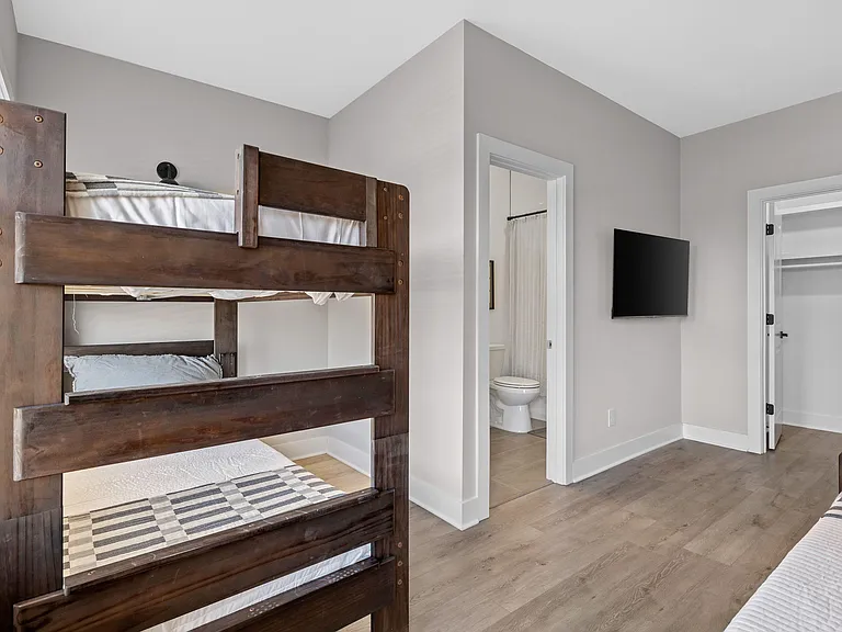 Spacious bedroom with sturdy bunk beds, ensuite bath access, and a wall-mounted TV plus nearby closet storage.