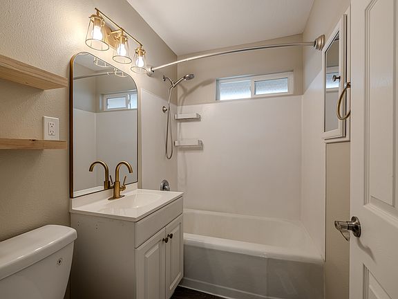 The bathroom features a handheld showerhead for easy pet cleaning, floating shelves for personalized decor, and a built-in medicine cabinet with a mirrored front.