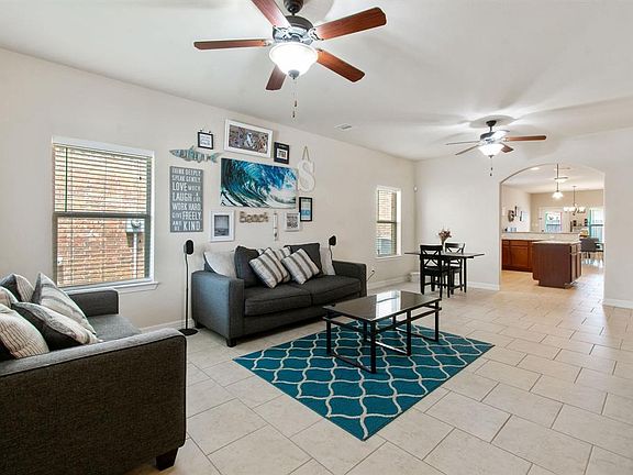 Large inviting living room with staggered tile and TWO ceiling fans. Notice space for game table or breakfast nook and arched entry into kitchen. Plenty of natural light!
