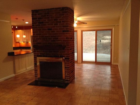 This is looking into the living room and dining room from the front door. Wood fireplace in between rooms with kitchen and twin sliding glass doors leading to back yard.