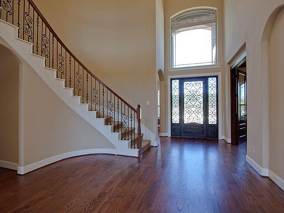    STUNNING ENTRY WITH WROUGHT IRON 8' FRONT DOOR AND SWEEPING STAIRCASE WITH WROUGHT IRON.
