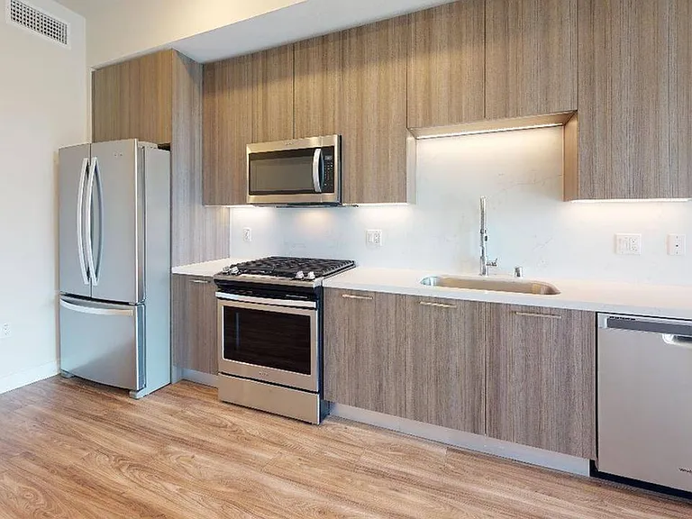 Stainless steel appliances and quartz countertops and backsplashes create a clean, modern look.