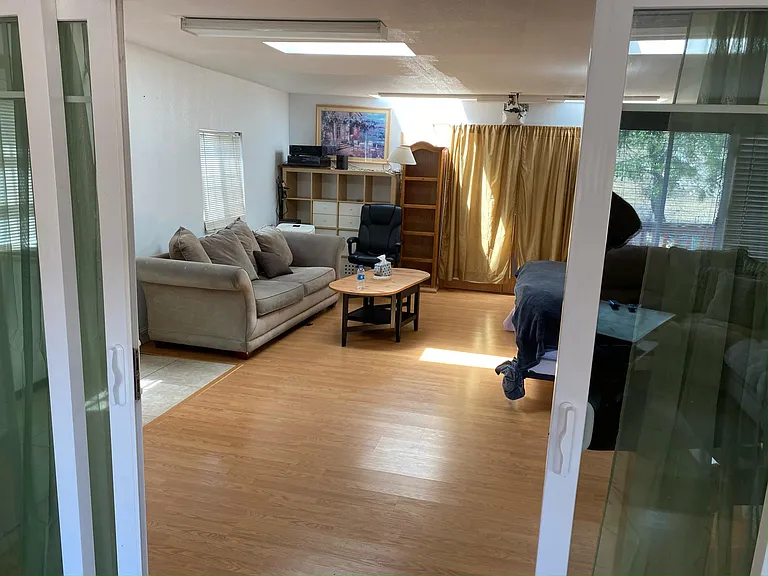 View of very large bedroom from living room (slider door with curtains for quiet and privacy) two sky lights make it very bright. Sitting area with fold out sofa. Access to small storage garage.