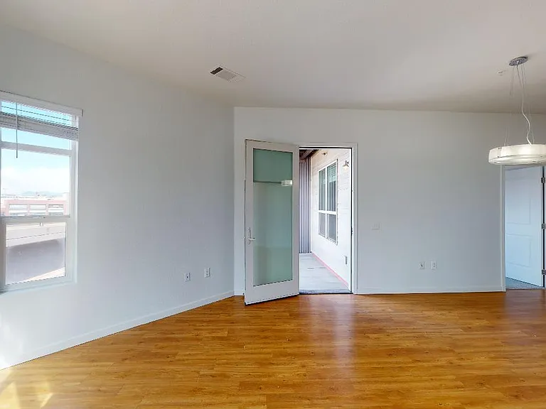 Apartment living room with wood-style flooring and balcony or patio in select homes.