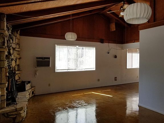Living room with stone fireplace and wall AC unit
