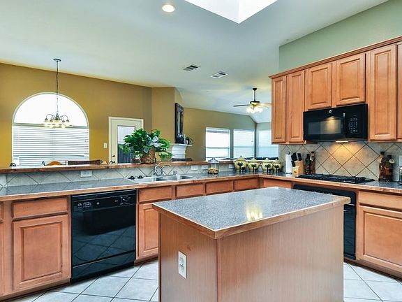 Bright and open kitchen with laminate counters trimmed in wood. Ceramic tile backsplash and ceramic 