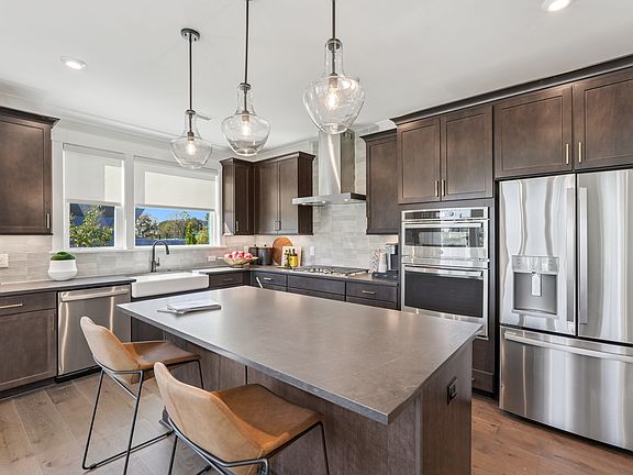 A modern, well-equipped kitchen with dark wood cabinets, stainless steel appliances, and pendant lig
