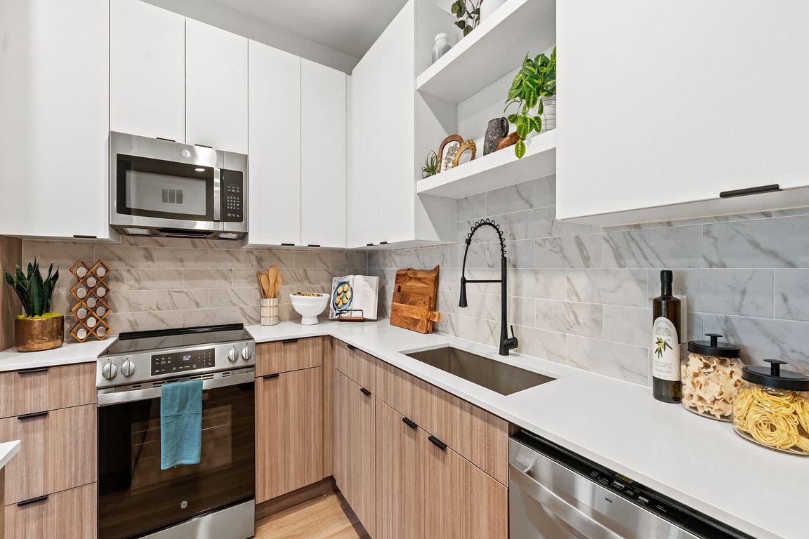 Modern kitchen with sleek white cabinets, stainless steel appliances, and elegant wood accents, perfect for culinary enthusiasts.