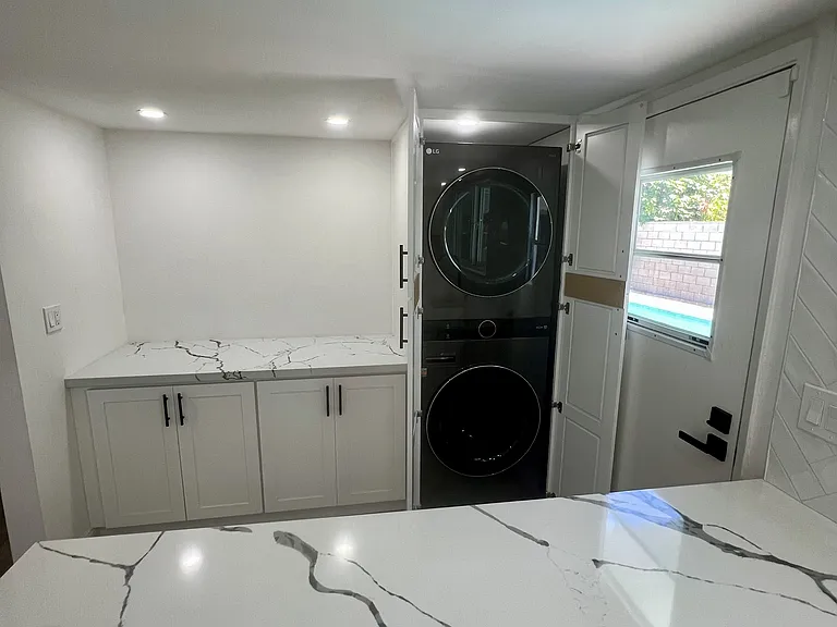 Stack LG washer and dryer next to large storage and countertop spaces