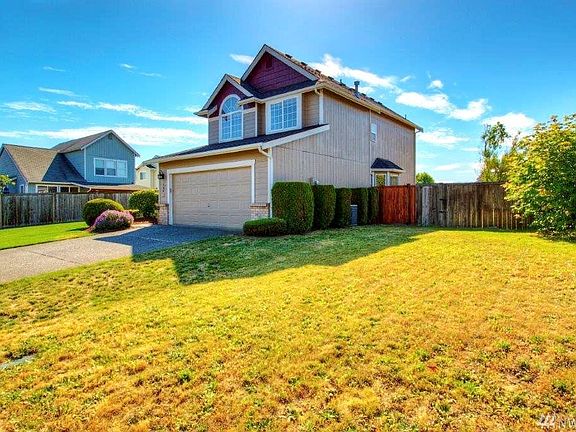 Right side of home showing manicured bushes and A/C unit hidden in the middle. 