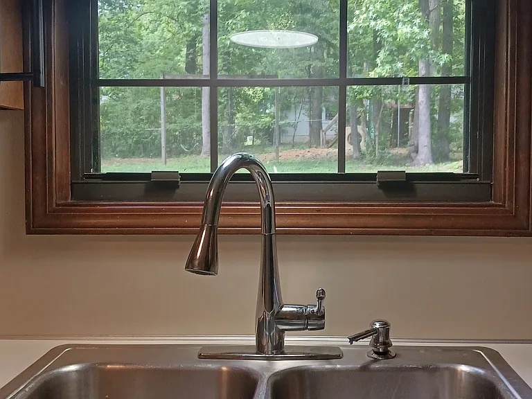 New kitchen faucet and lighting with view to backyard.