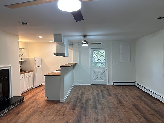 View of the living/dining/kitchen from inside, toward the unit entrance. Floors are vinyl