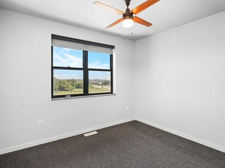 Bright and airy bedroom with a stylish ceiling fan, large window offering scenic views, and fresh carpeting. Bright and airy bedroom with a stylish ceiling fan, large window offering scenic views, and fresh carpeting.
