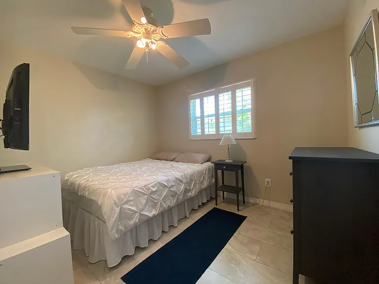 Bedroom/den furnished with a queen bed and dressers for storage.