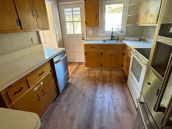 Kitchen with new floors, dishwasher, kitchen sink hardware, and overhead lighting.