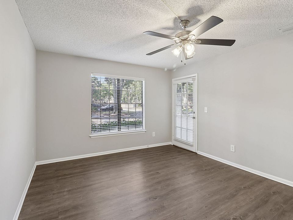 Bright room with elegant wood flooring, large window, and modern ceiling fan, perfect for comfortable living.
