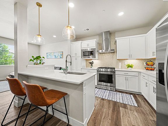 Upgraded kitchen with quartz countertops, under cabinet lighting, gas stove with hood, large island