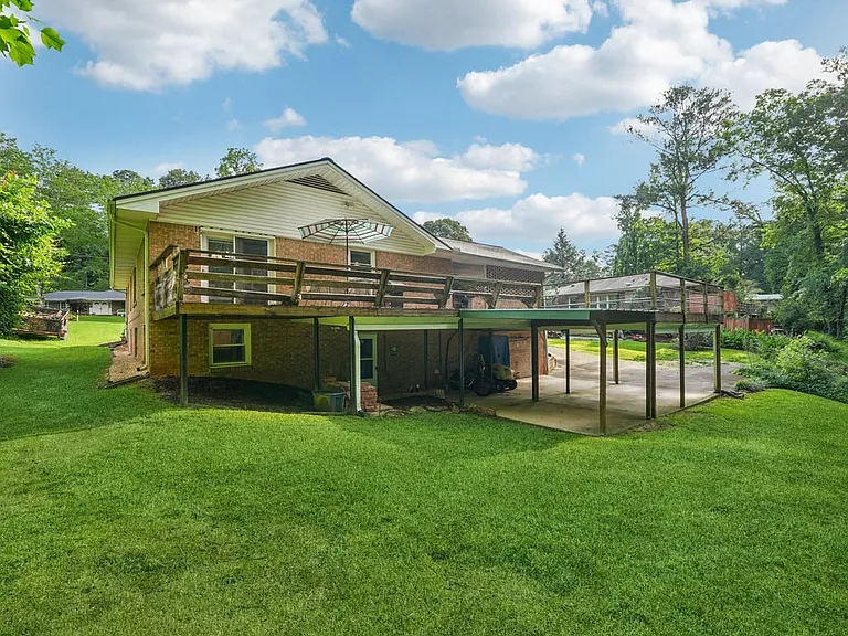 A lush backyard retreat where the elevated deck, sweeping green lawn, and peaceful wooded surroundings create a magical outdoor escape made for gathering and relaxing.