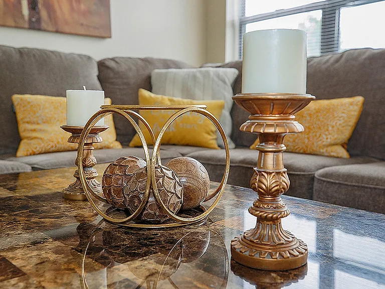 Elegant living room with stylish decor, featuring a marble coffee table adorned with ornate candlesticks and decorative accents, all set against a comfy sofa with plush cushions.
