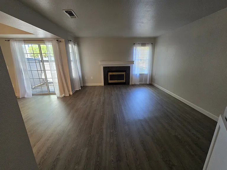 Spacious living room with cozy fireplace, luxury plank flooring, and sliding glass doors leading to your second private outdoor deck.