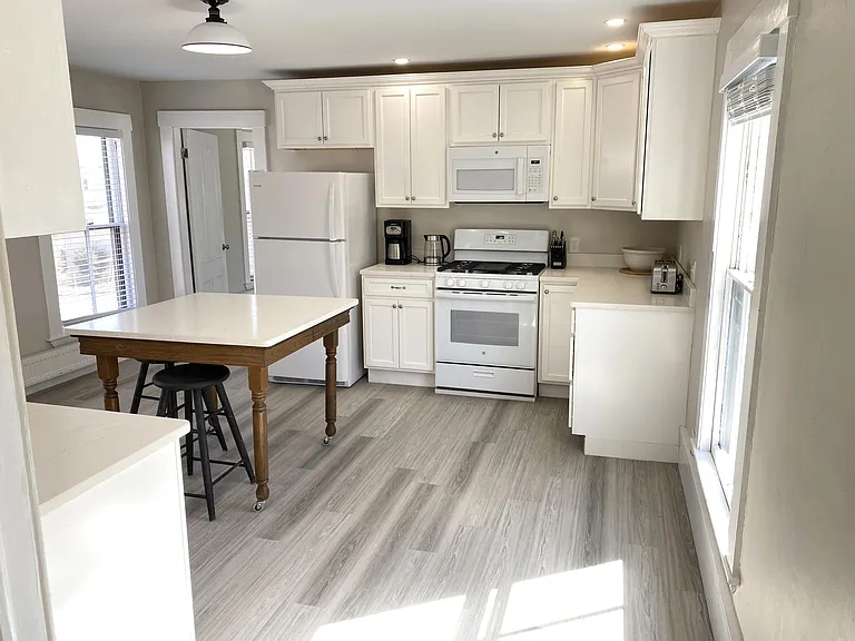 There is plenty of sunshine in this large kitchen. You will enjoy custom cabinets, quartz countertops and gas range. Door leads to bedroom.