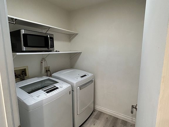 Large laundry room with storage shelves and full-sized washer and dryer, skylight.