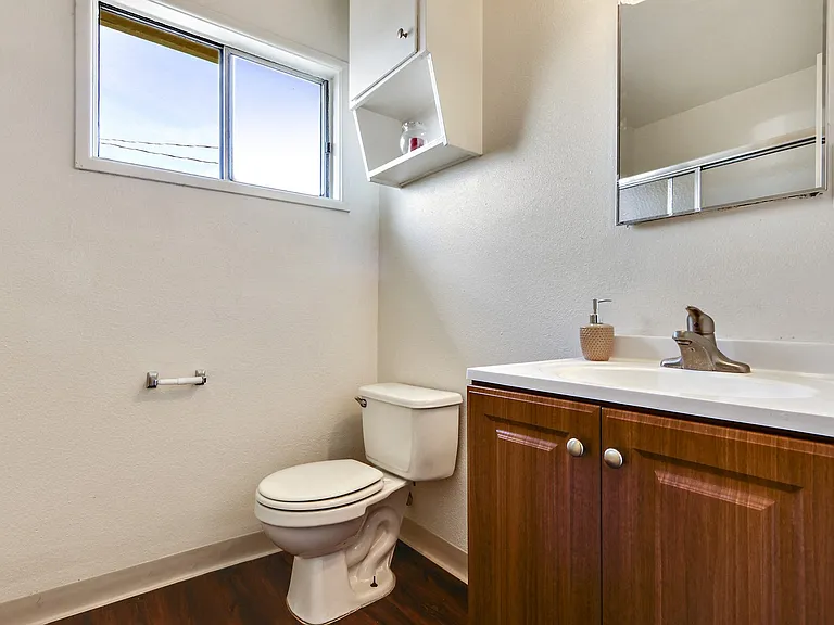 Bathroom with wood style single vanity, White single cabinet above the toilet