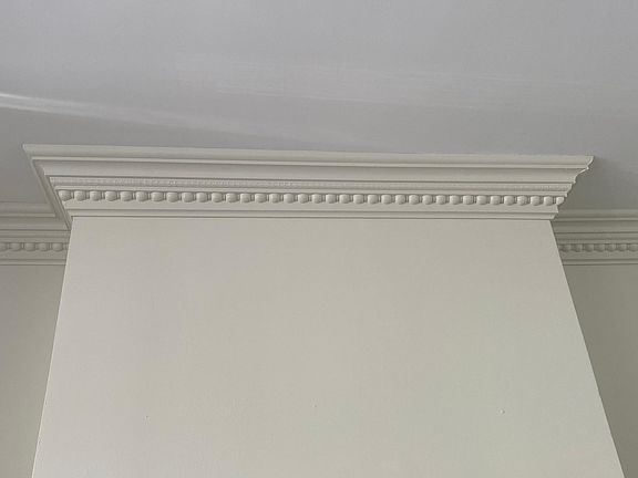 Egg and dart ceiling molding above fireplace in living room