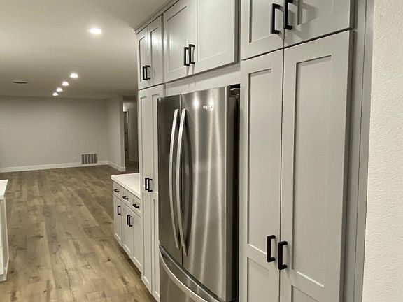 Recessed stainless steel refrigerator flush with pantry cabinets