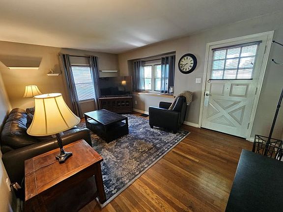 Living Room Entry - Sunlit windows, polished hardwood floors, comfortable furnishings.