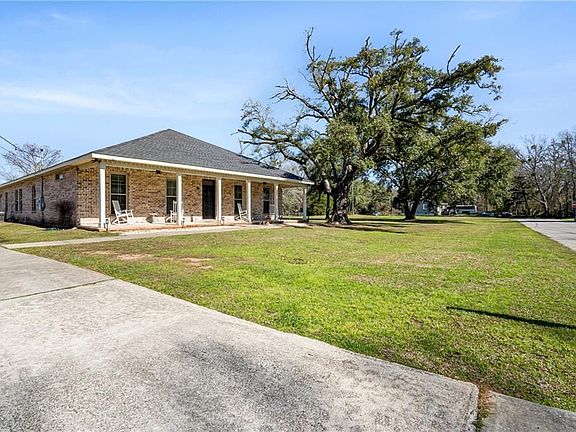 View of front of property featuring a shingled roof, a front yard, and brick siding