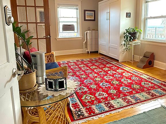 Entrance into living room with full-sized wall bed and french doors.