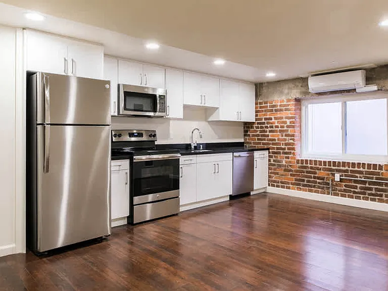 Kitchen with Stainless Steel Appliances and Living Area with Resurfaced Wood Floors