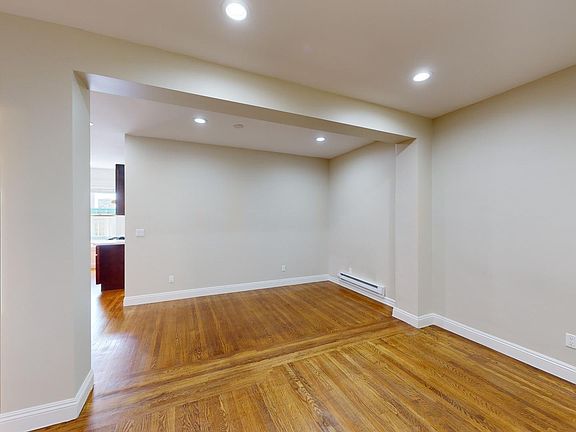 Bright, spacious room with hardwood floors, and recessed lighting; archway leads to another area.