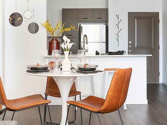 Apartment kitchen with stainless steel appliances and dining room with wood-style flooring.